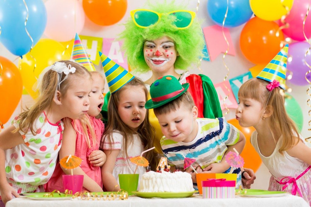 kids at a birthday party blowing birthday cake