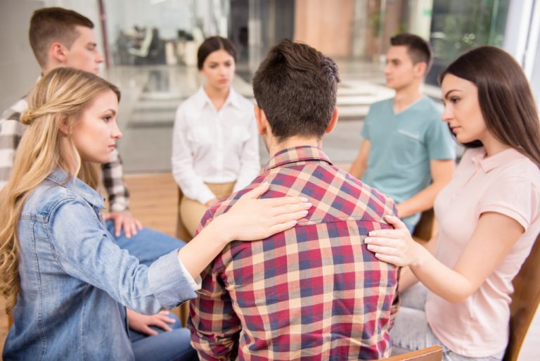 man being held in his back by his support group in a meeting