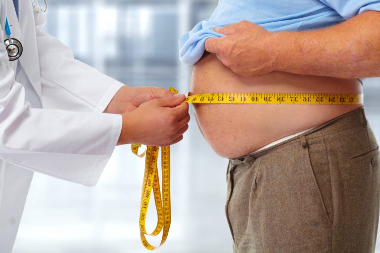 doctor measuring man's waistline