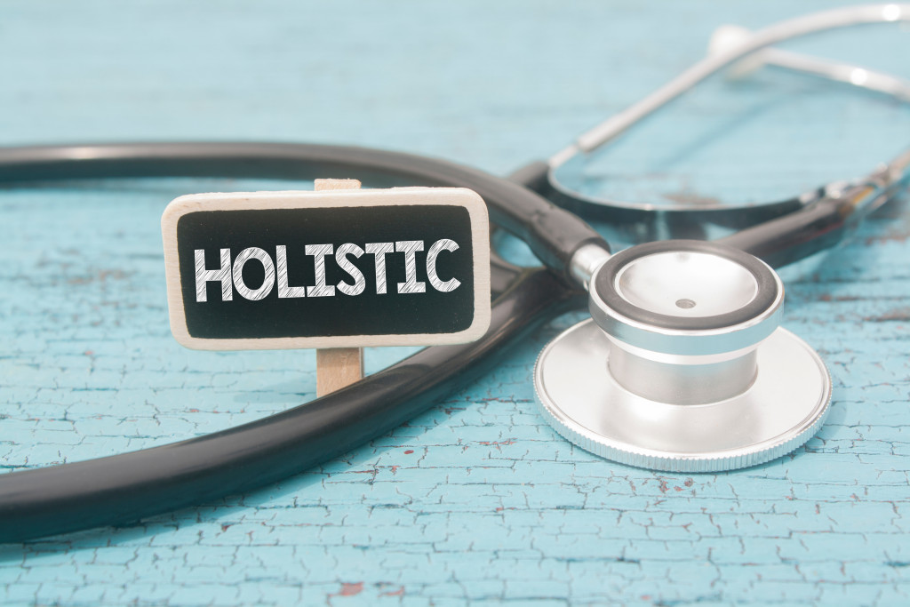 stethoscope and wooden background written holistic over it