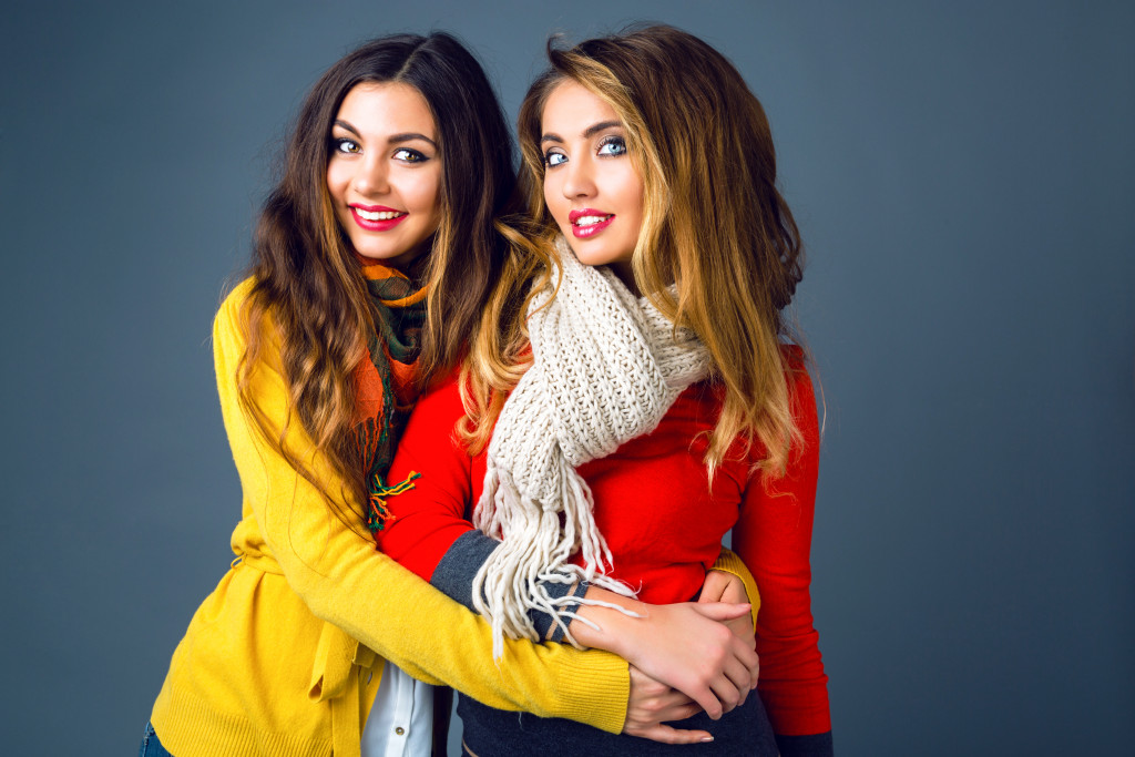 two women wearing scarves and cardigans