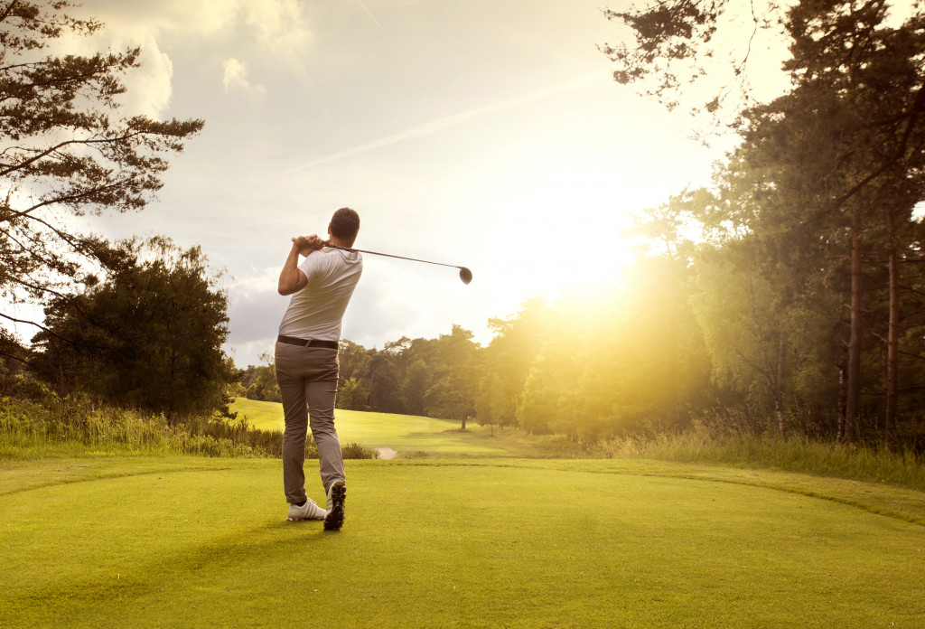 man playing golf in open field in sunny day