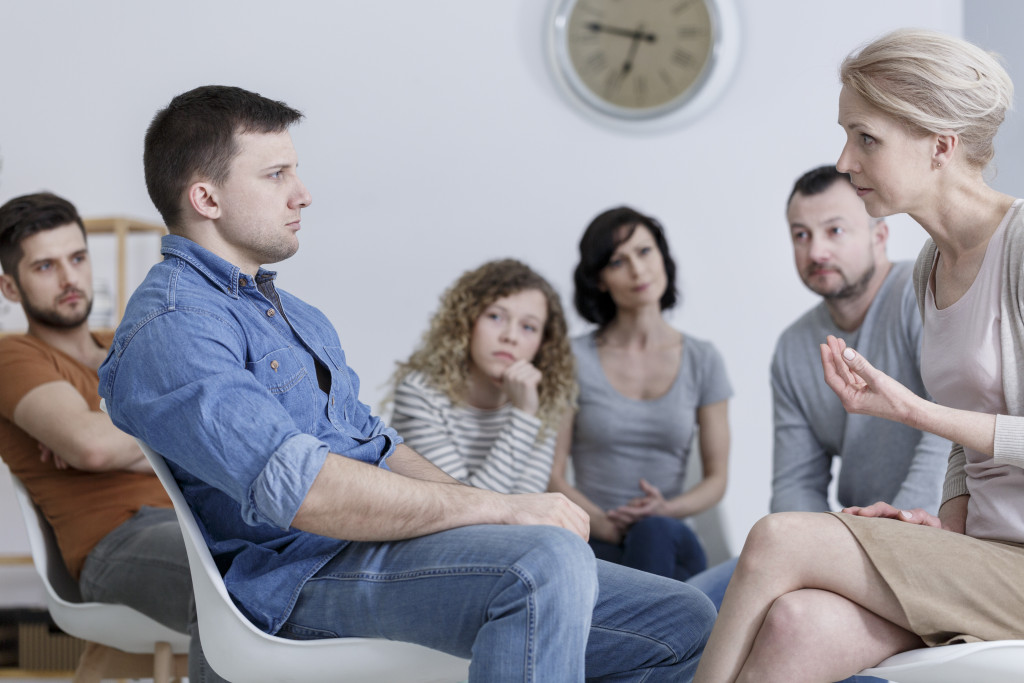 a group counseling session with a man listening to a female counselor