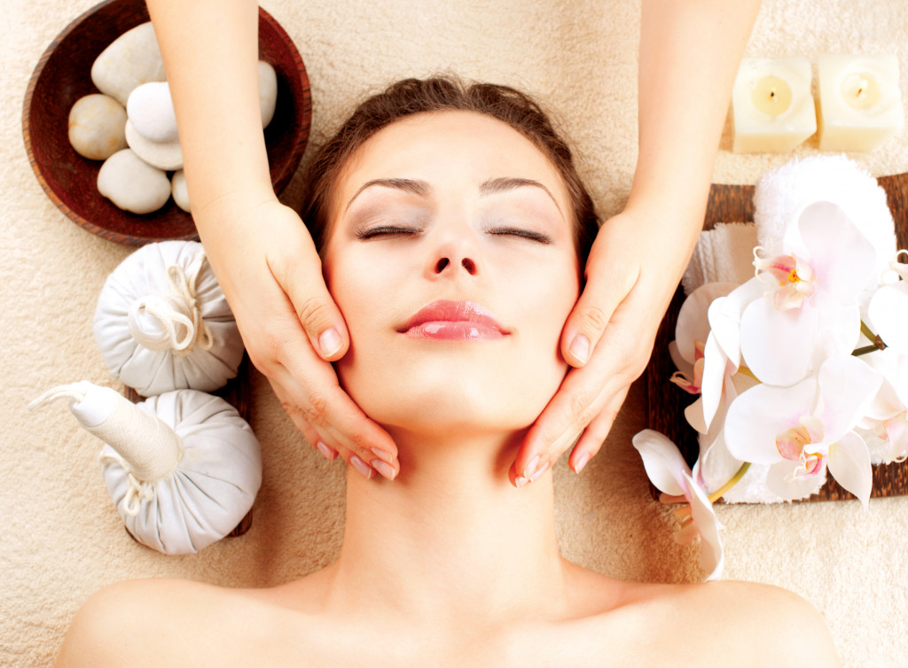 a sleeping woman smiling while aesthetician massages her face