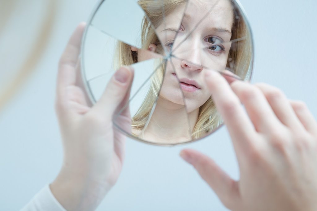 young woman holding a broken mirror