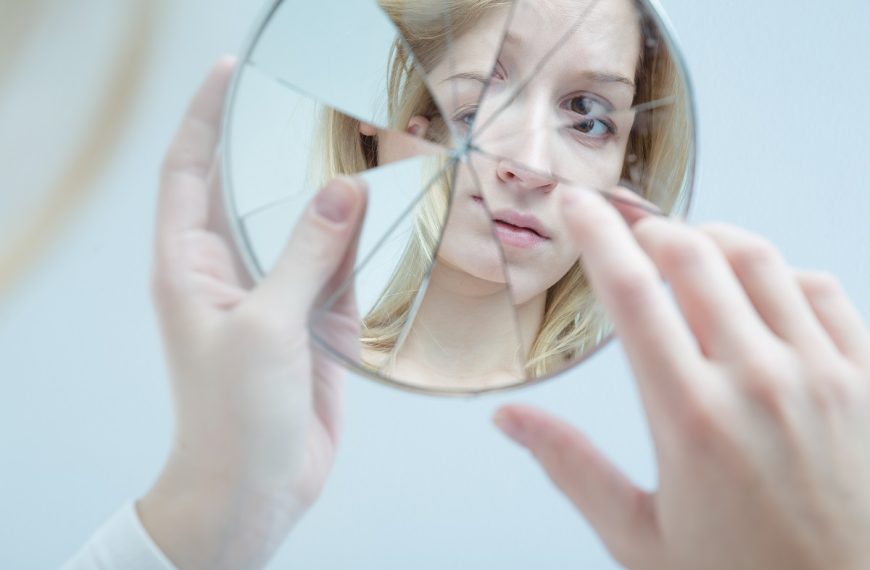 young woman holding a broken mirror