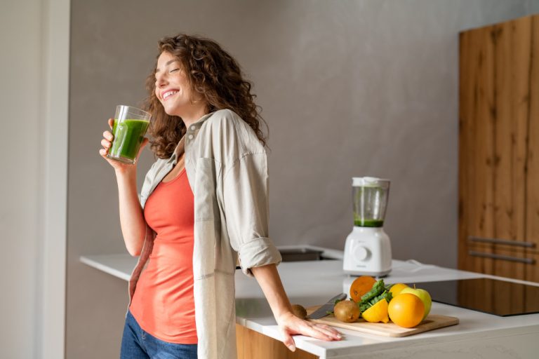 health enthusiast woman drinking green smoothie in her house